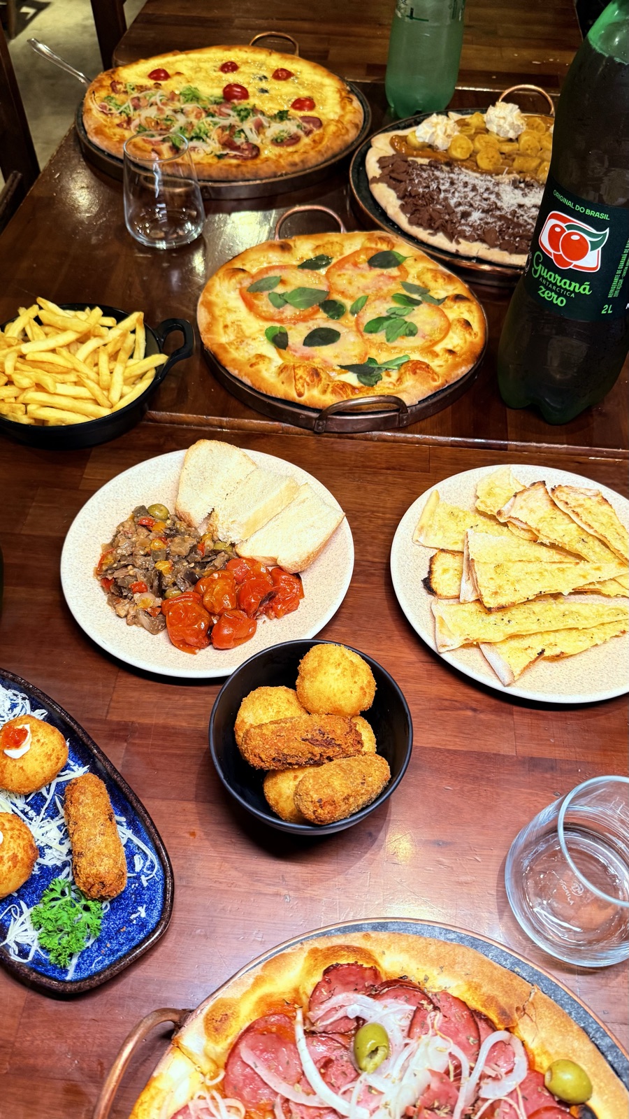 Mesa do rodízio com pizzas, entradas e batata frita
